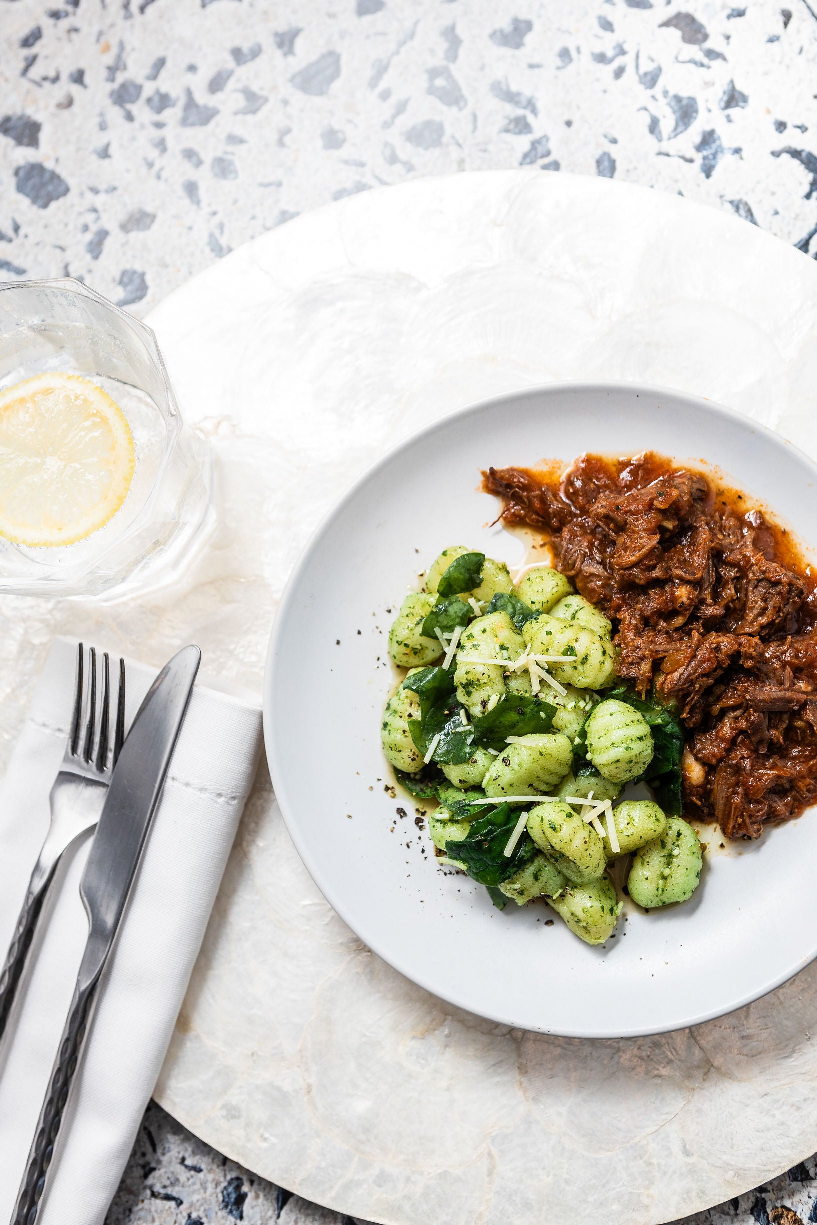 Plate of Brubecks gnocchi with a side of meat sauce on a marble surface