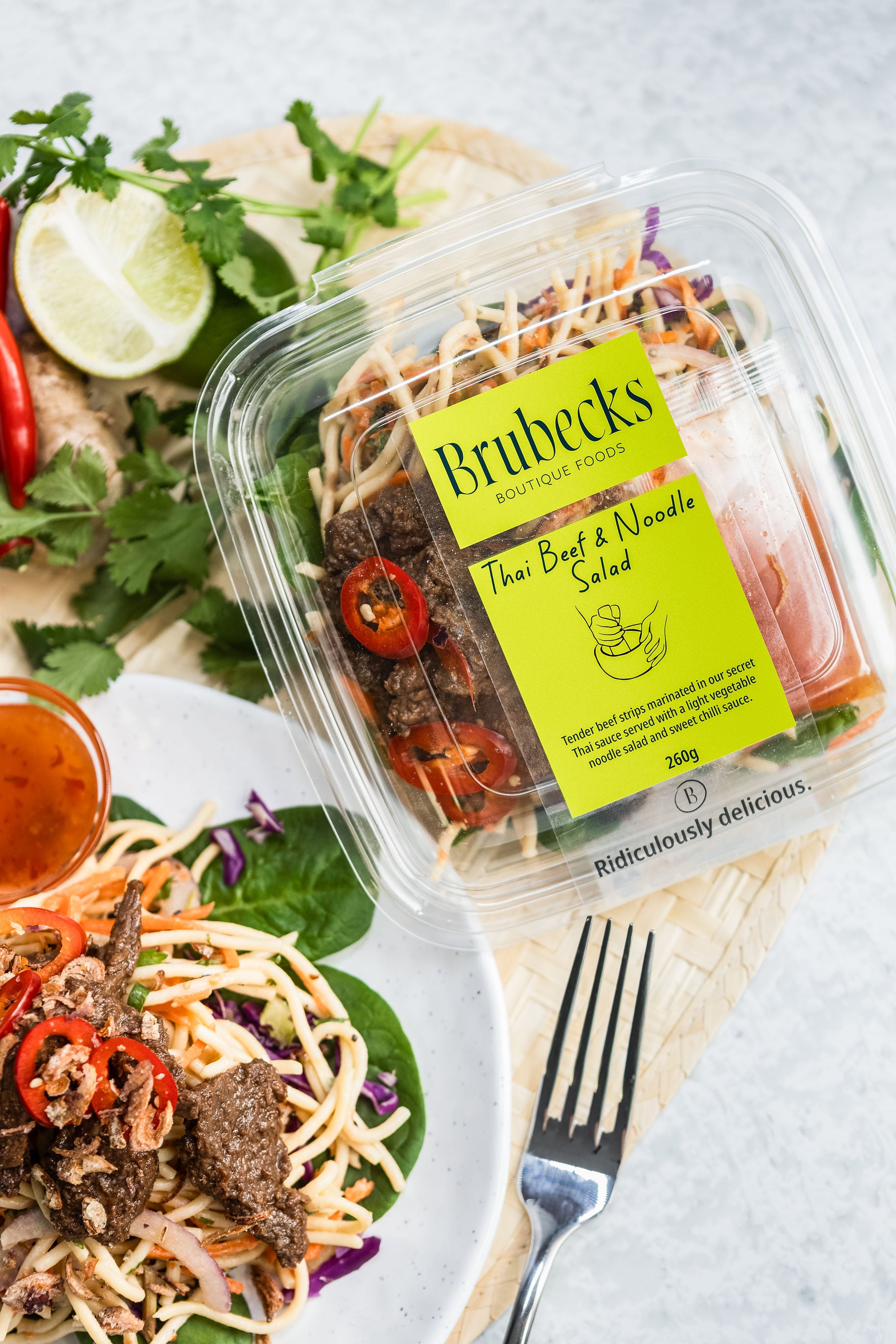 Brubeck's Thai Beef & Noodle Salad packaging with a salad on a plate in the background.