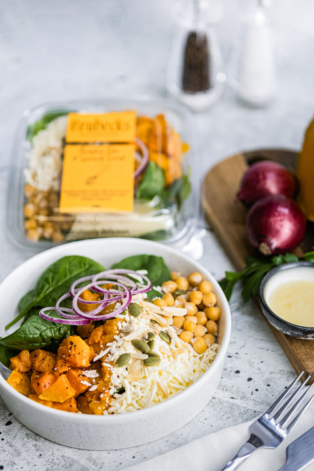 Healthy salad bowl with chickpeas, spinach, and cheese on a concrete surface.