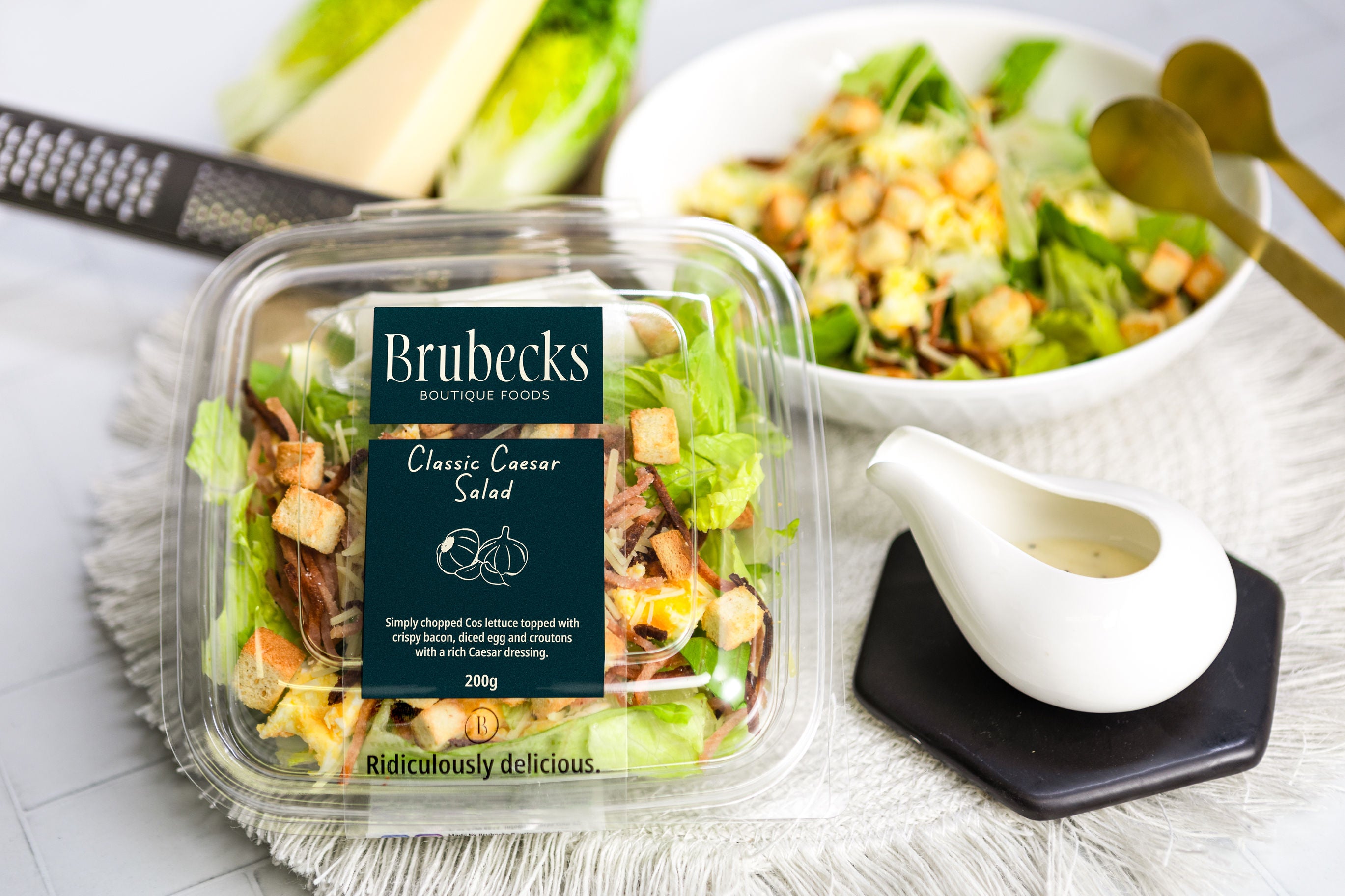 Brubecks Classic Caesar Salad packaging with a salad bowl and dressing on a table.