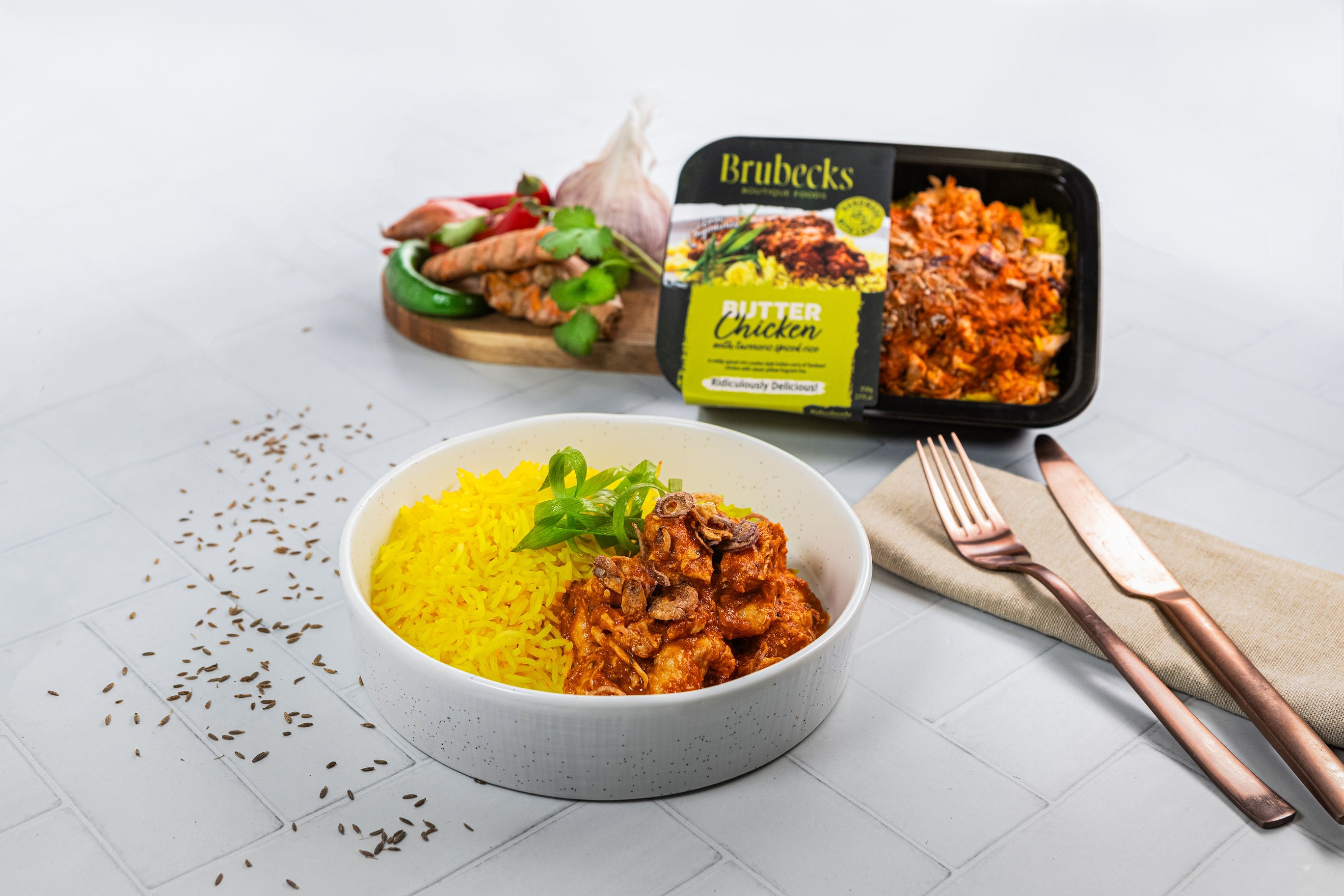 Bowl of yellow rice with chicken and a Brubecks food packaging on a white surface.