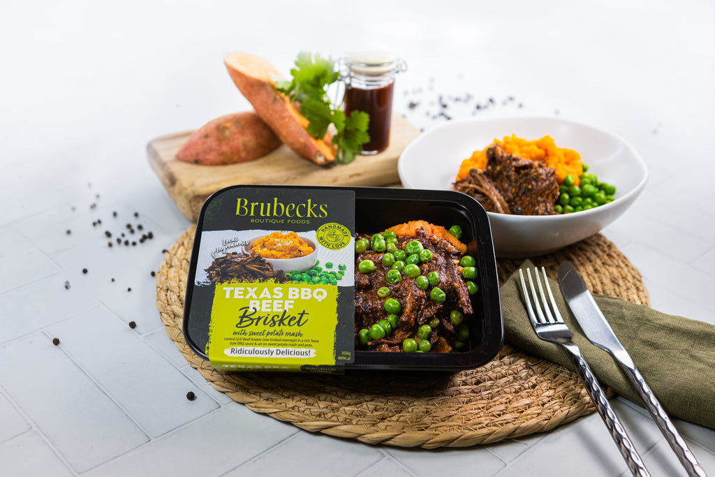 Brubeck's Texas BBQ Beef Briket packaging with a meal setup including peas, carrots, and a fork on a white surface.