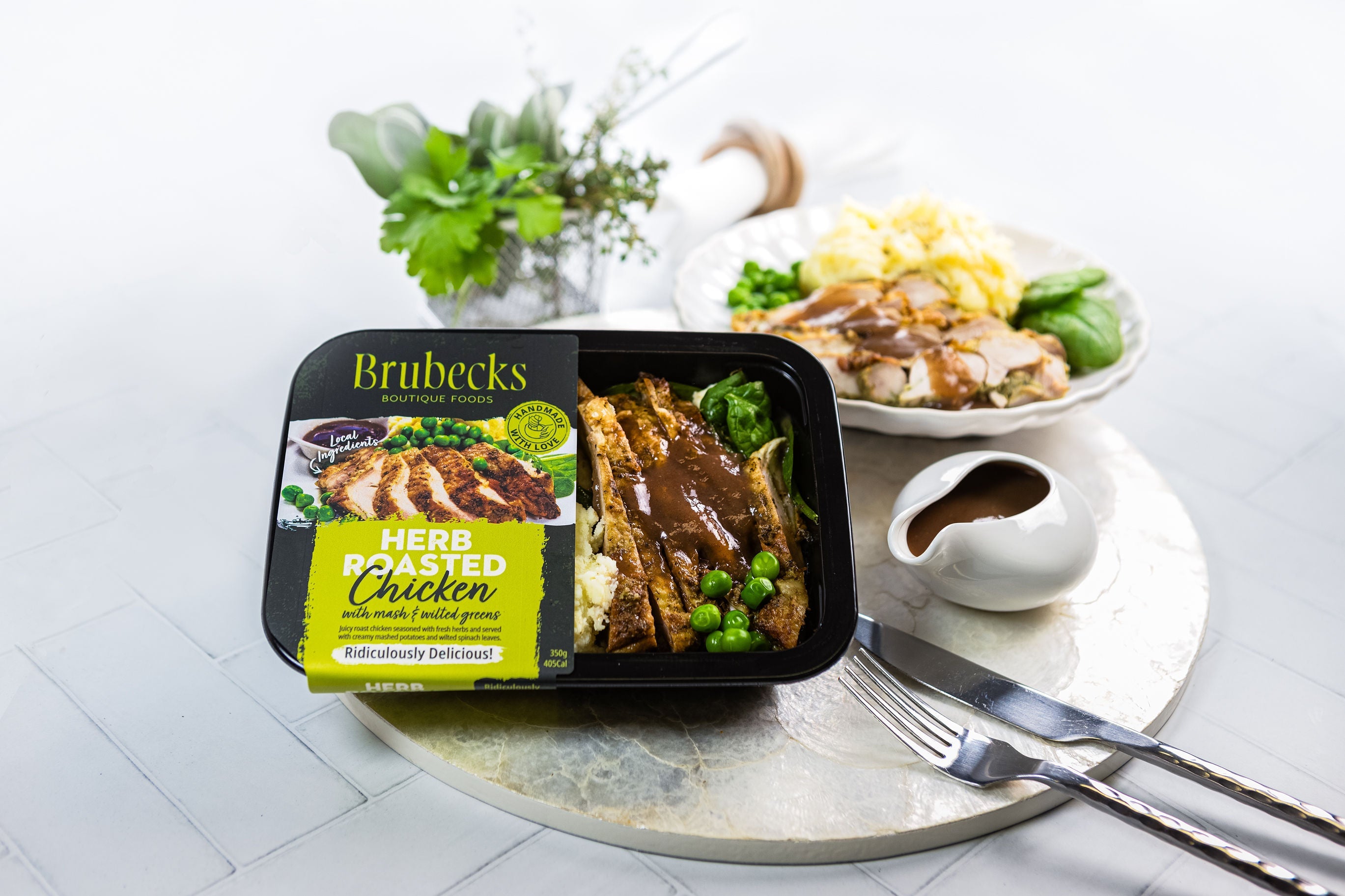 Brubecks herbed roasted chicken packaging on a table with a dish of chicken and vegetables.