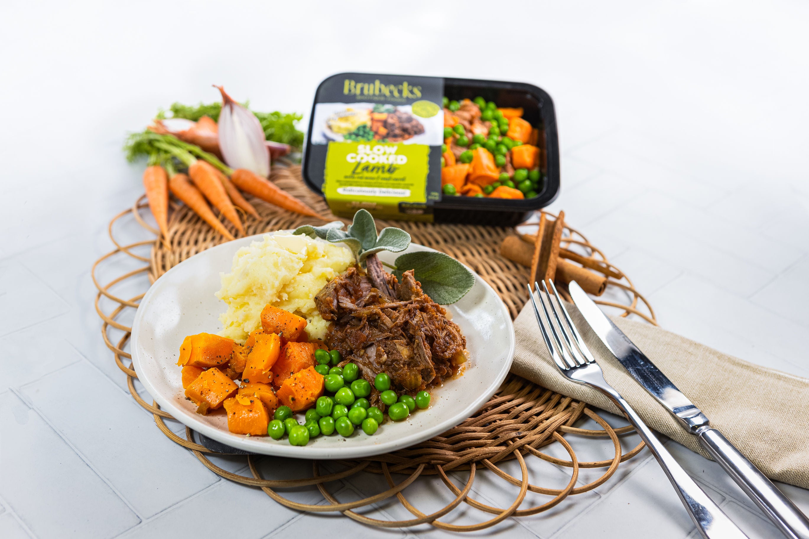 Plated meal with beef, carrots, and peas next to a Brubecks packaging on a white surface.