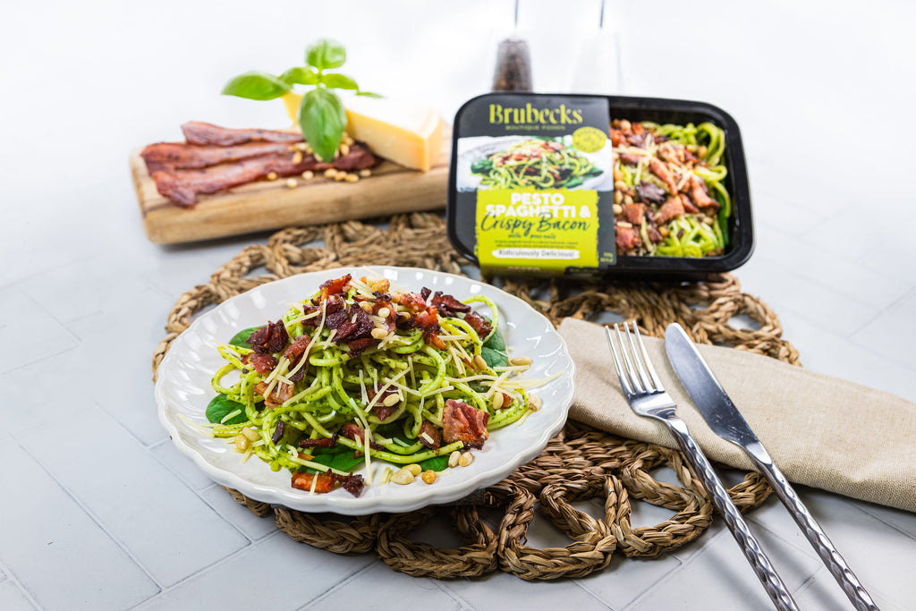 Salad with green noodles and bacon on a white plate, with Brubecks pasta packaging in the background.