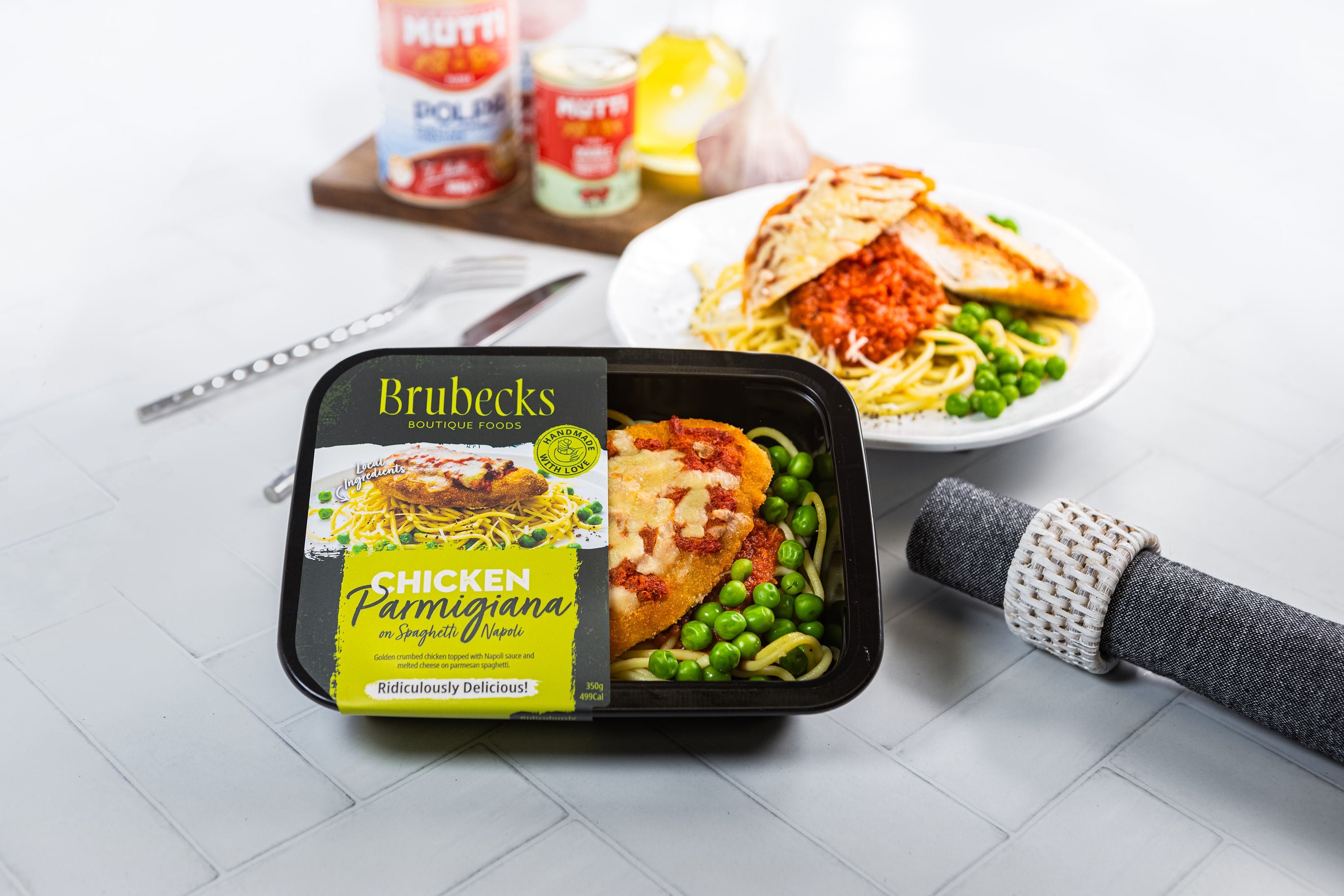 Brubeck's Chicken Parmigiana meal package on a table with a plate of pasta and salad.