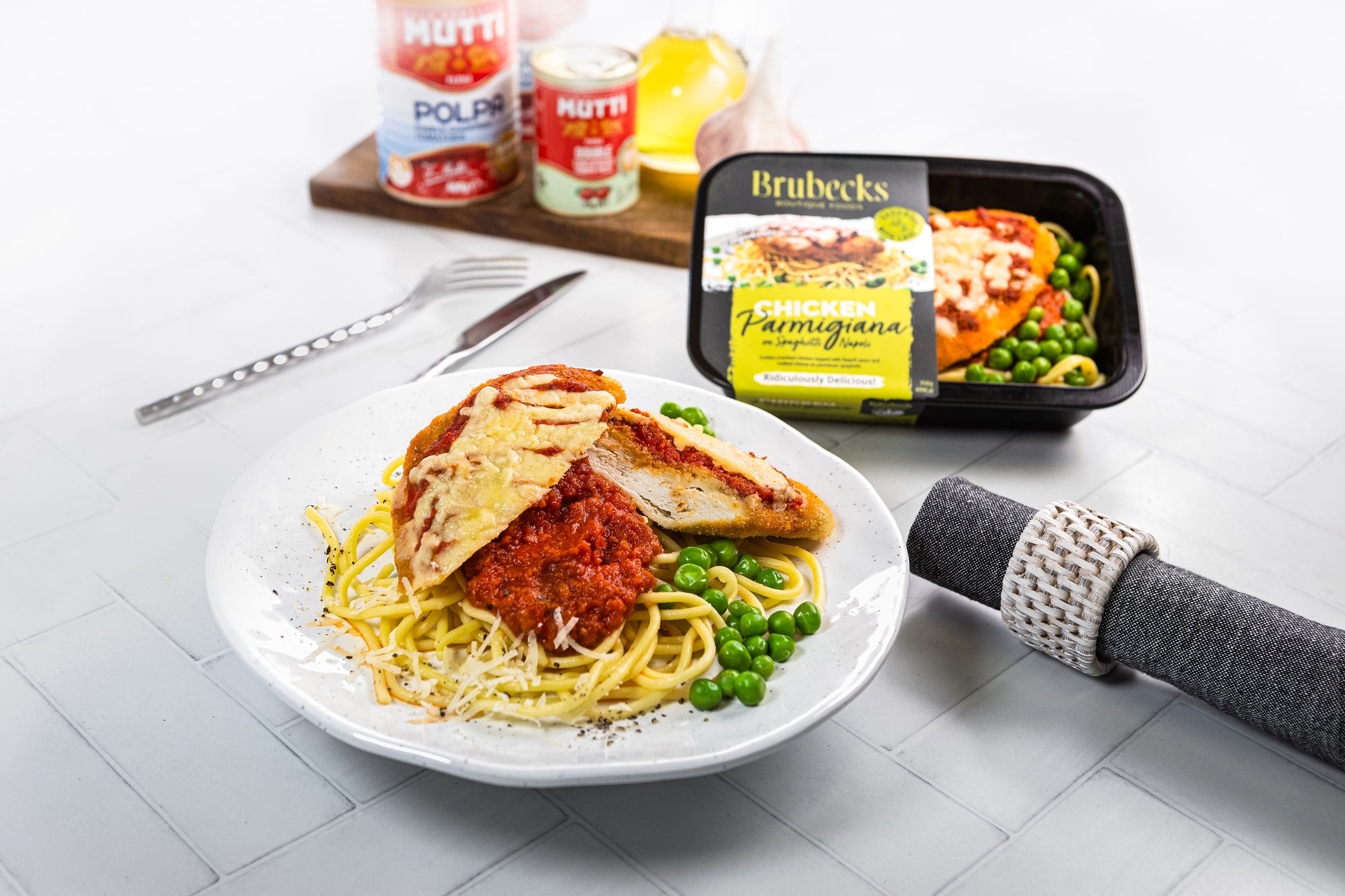 Plate of spaghetti with meat sauce and peas, Brubeck's packaging on a white surface.
