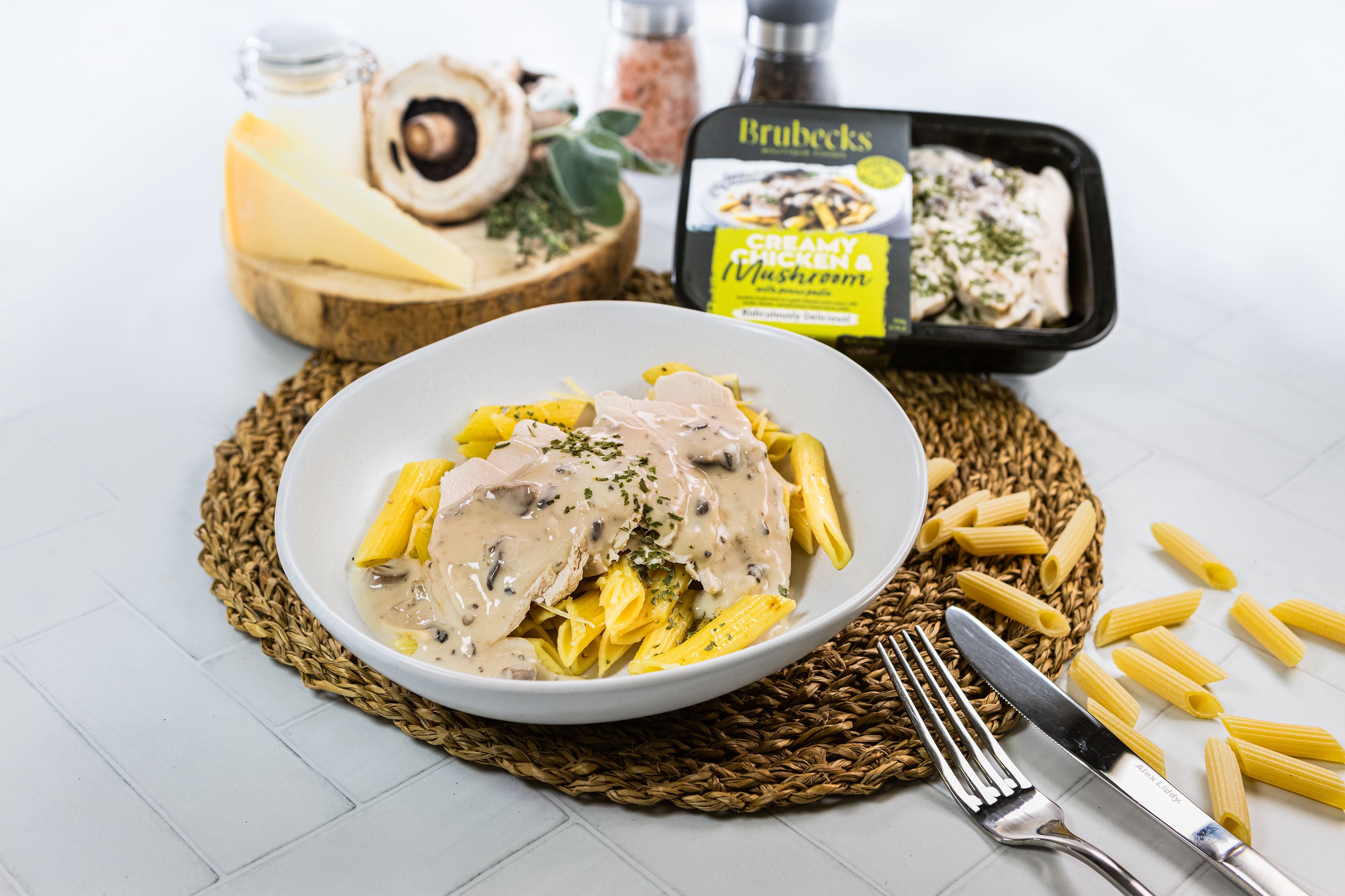 Pasta dish with creamy sauce in a white bowl, surrounded by Brubeck's product packaging and ingredients on a white surface.