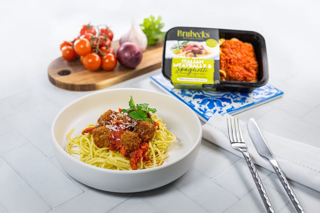 Bowl of spaghetti with meatballs on a table with Brubeck's Italian Meatballs packaging.