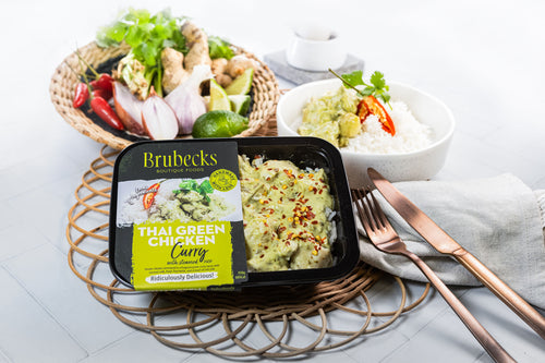 Brubecks Thai Green Curry package on a table with a fork and knife, and a bowl of salad in the background.