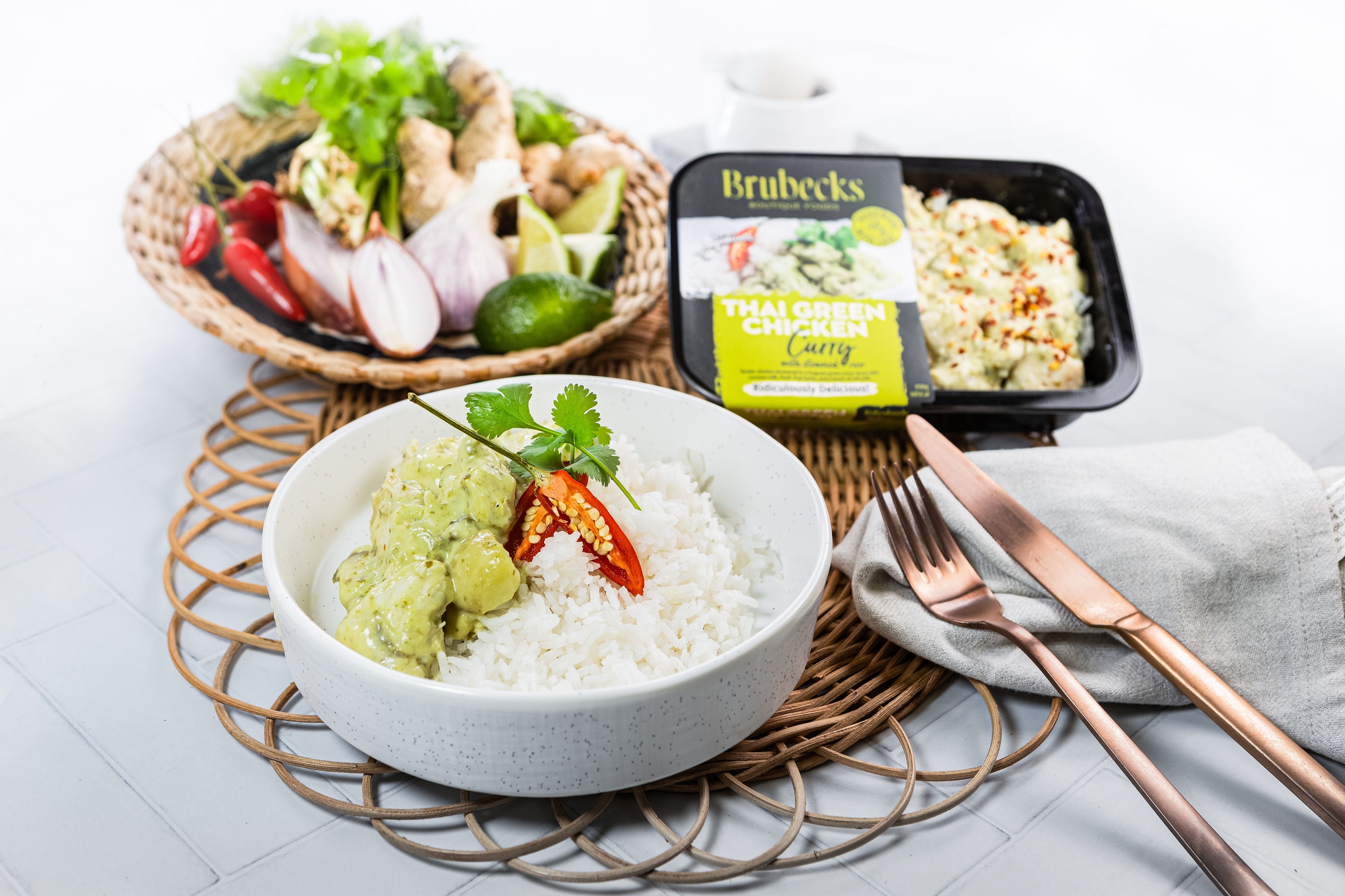 Bowl of rice with green sauce, Brubecks container, and ingredients on a white surface