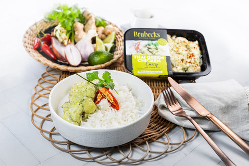 Bowl of rice with green sauce, Brubecks container, and ingredients on a white surface