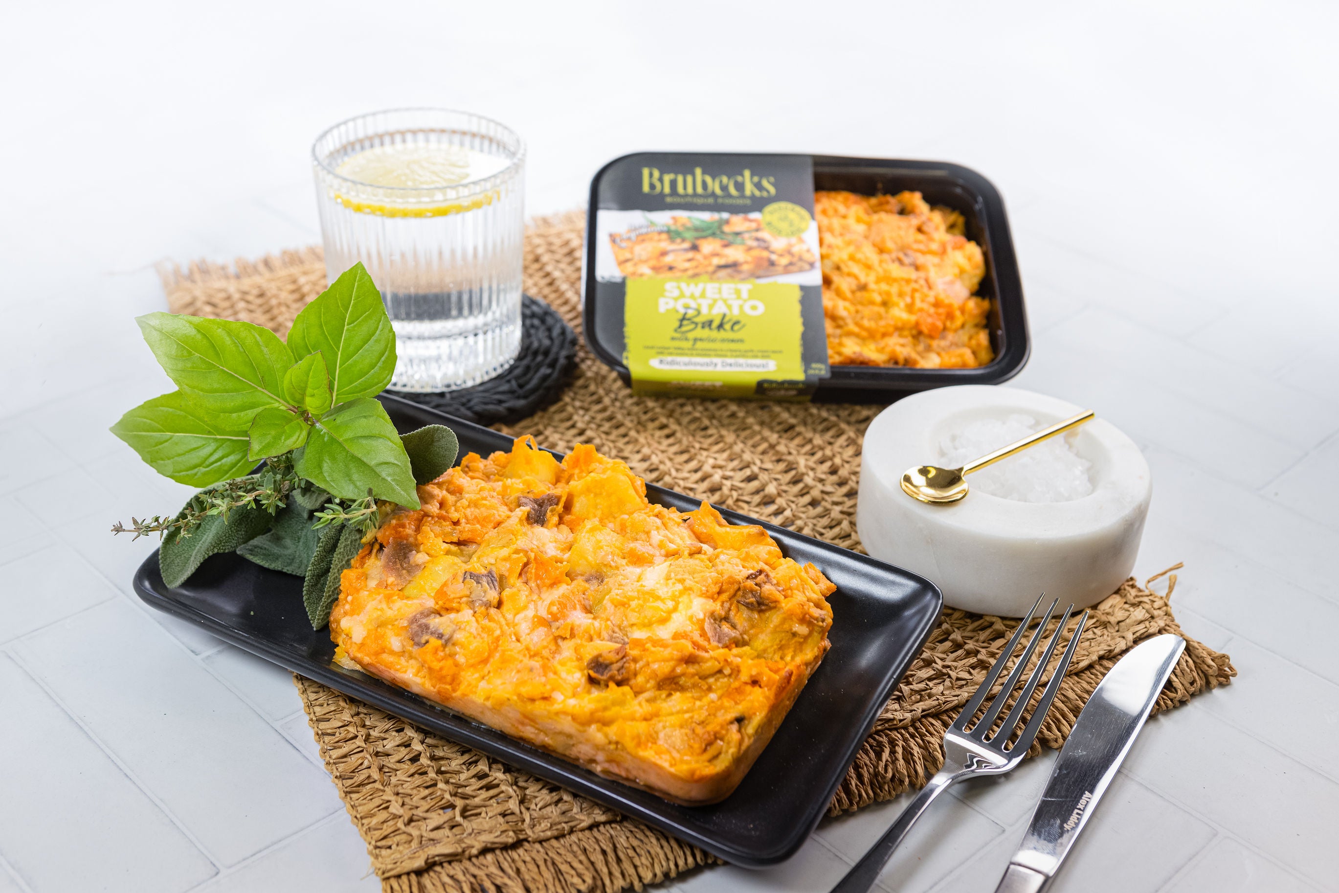 Plated dish of macaroni and cheese with a glass of water and Brubecks packaging on a white surface.