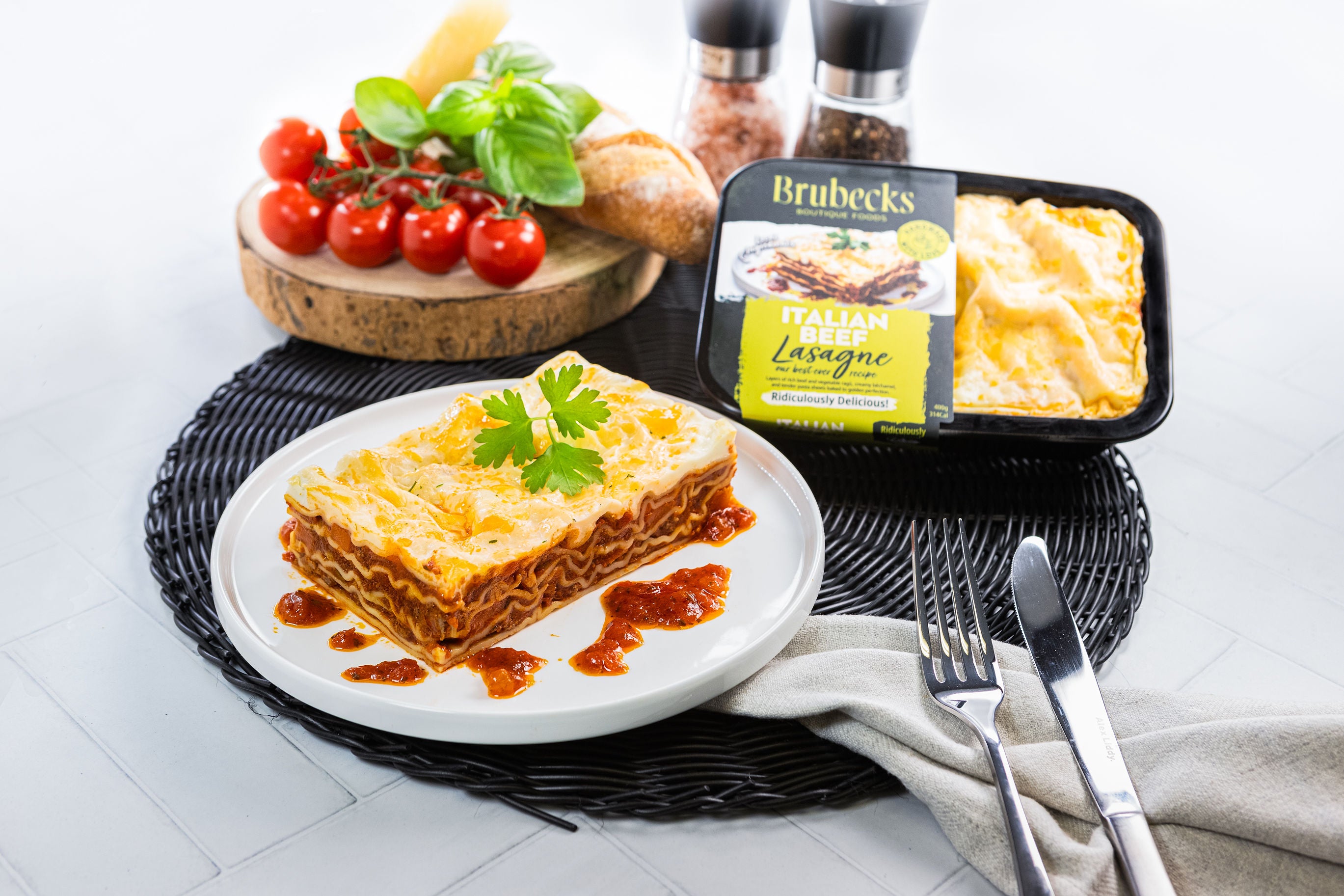 Brubeck's Italian Lasagne with a plate of lasagne and fresh ingredients on a white background