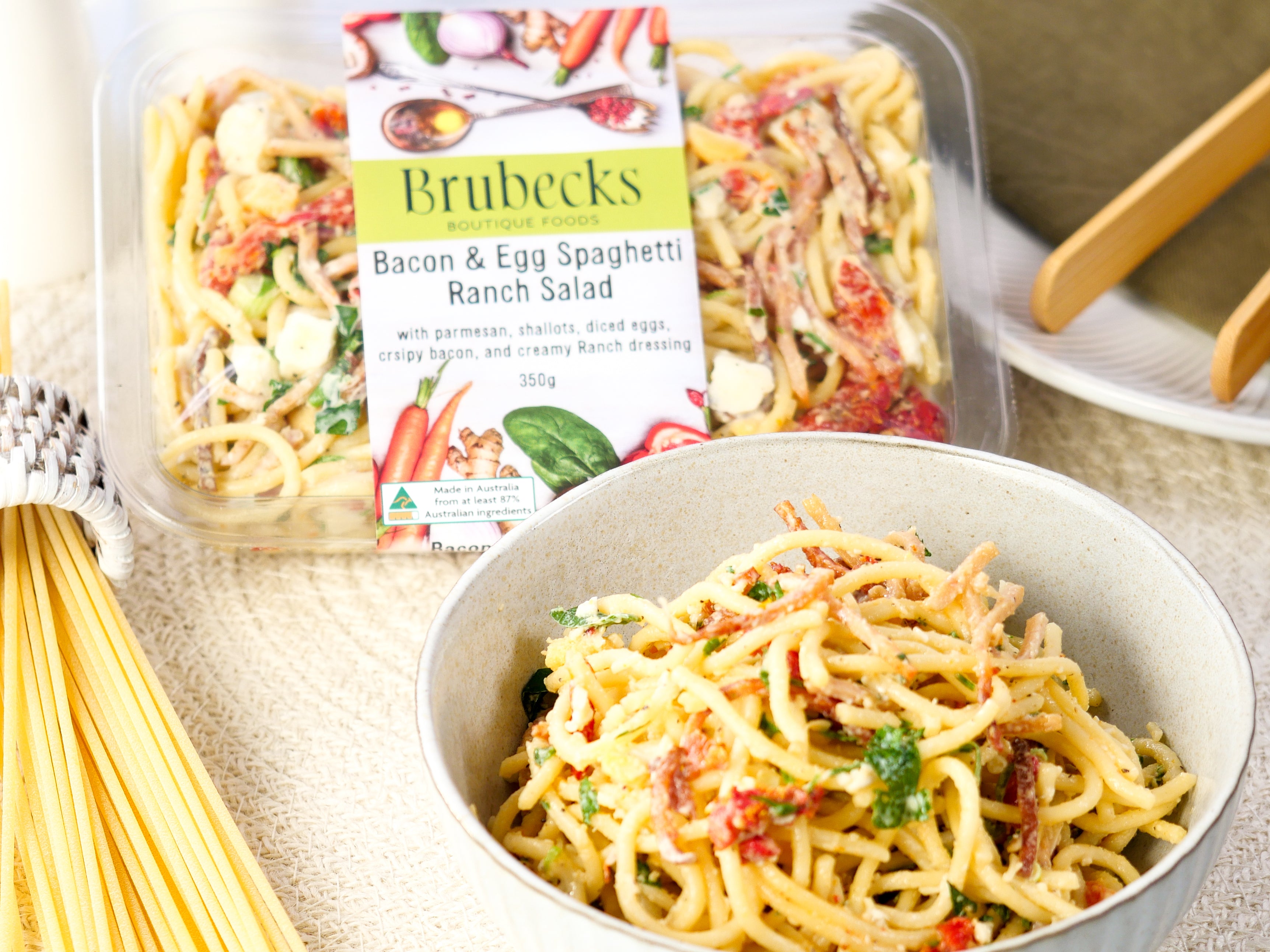 Brubecks Bacon & Egg Spaghetti Ranch Salad packaging with a bowl of salad on a table.