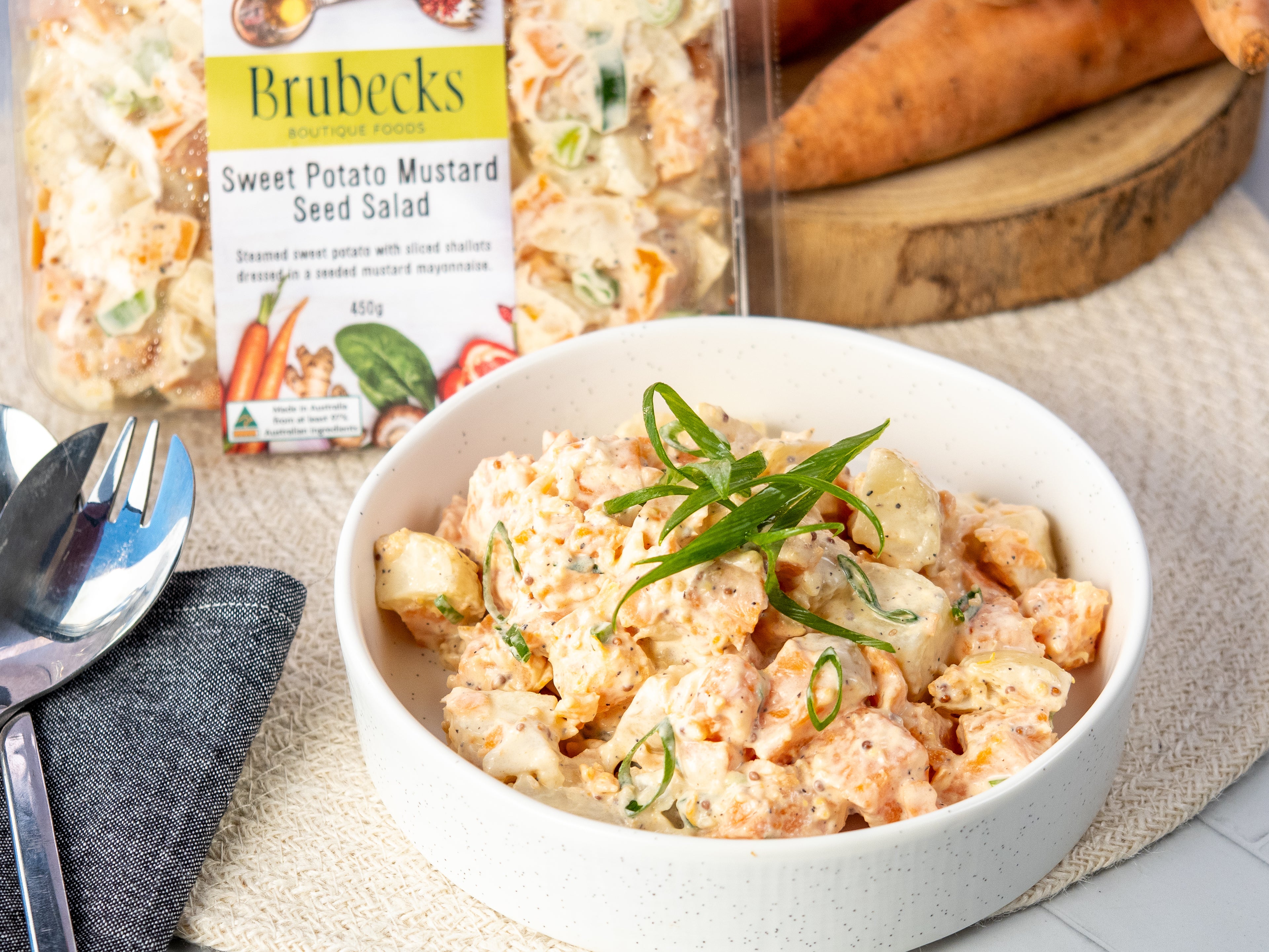 Brubeck's Sweet Potato Mustard Seed Salad in a bowl with packaging and carrots in the background.