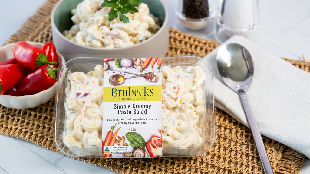 Brubecks Simple Creamy Pasta Salad packaging on a table with ingredients and utensils.