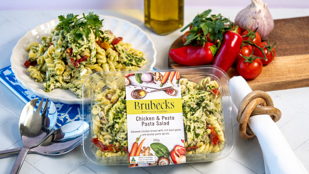 Brubeck's Chicken & Pesto Pasta Salad packaging with a pasta salad dish and ingredients on a table.