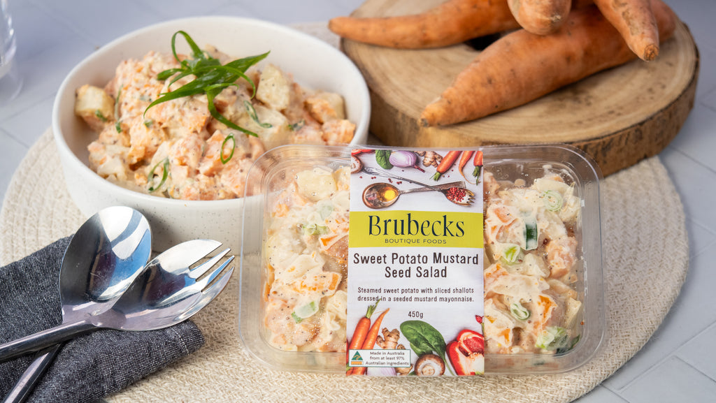 Brubecks Sweet Potato Mustard Seed Salad packaging with a bowl of salad and carrots on a wooden board.