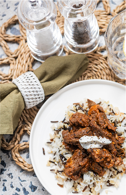 Plated dish of rice with curry and a salt and pepper shaker on a woven mat.